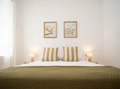 a bedroom with a bed with two pictures on the wall at SibsSanlucar Duquesa Loft Coqueto Ideal Parejas in Sanlúcar de Barrameda