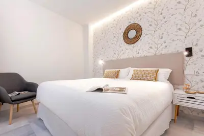 a bedroom with a large white bed and a chair at Genteel Home Catedral Cádiz in Cádiz