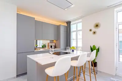 a kitchen with white counter chairs and a kitchen island at Genteel Home Catedral Cádiz in Cádiz