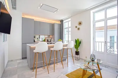 a kitchen with white stools and a counter top at Genteel Home Catedral Cádiz in Cádiz