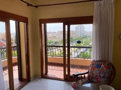 a room with a chair and a balcony with sliding glass doors at Apartamento Acuario in Sanlúcar de Barrameda