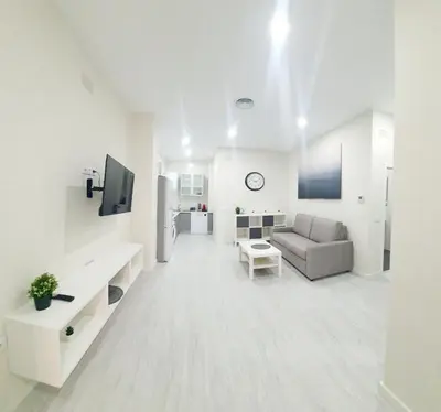 a white living room with a couch and a tv at Apartamento Plaza Calzada 1 in Sanlúcar de Barrameda