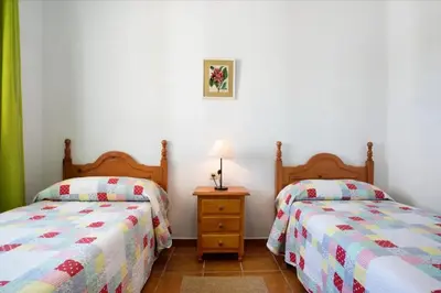 a bedroom with two beds and a table with a lamp at CHALET ROBLES in Cádiz