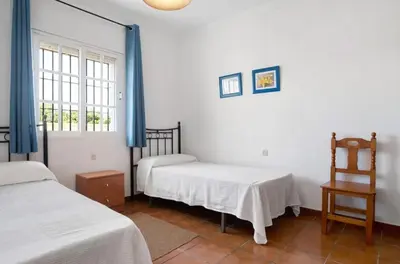 a white room with two beds and a window at CHALET ROBLES in Cádiz