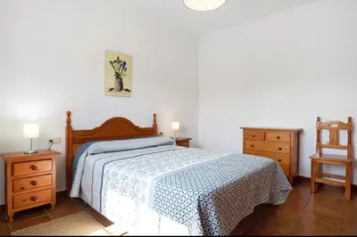 a bedroom with a bed and two night stands and a chair at CHALET ROBLES in Cádiz