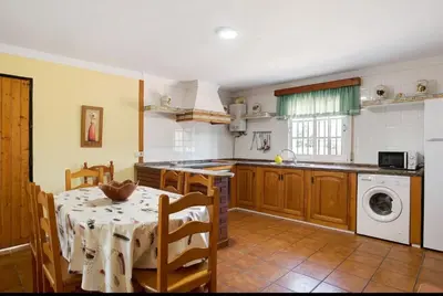 a kitchen with a table and a sink and a washing machine at CHALET ROBLES in Cádiz