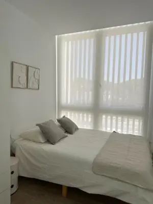 a bedroom with a white bed with a large window at VILLA SARAH Barrosa Playa in Chiclana de la Frontera