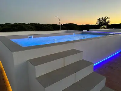 a swimming pool with blue lights on a building at VILLA SARAH Barrosa Playa in Chiclana de la Frontera