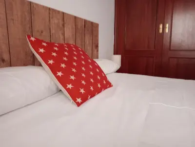 a red pillow sitting on top of a bed at Las Américas by RentCadiz in El Puerto de Santa María