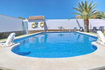 a swimming pool with blue water in front of a house at Chalet Cielo Azul in Conil de la Frontera