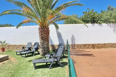 a group of chairs sitting under a palm tree at Chalet Cielo Azul in Conil de la Frontera