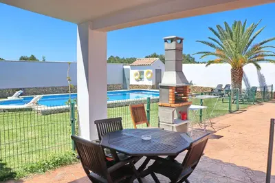 a patio with a table and a grill next to a pool at Chalet Cielo Azul in Conil de la Frontera