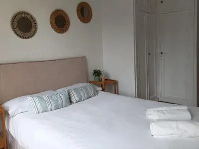 a bed with white sheets and pillows on it at 2 dormitorios y muy fácil aparcamiento in Jerez de la Frontera