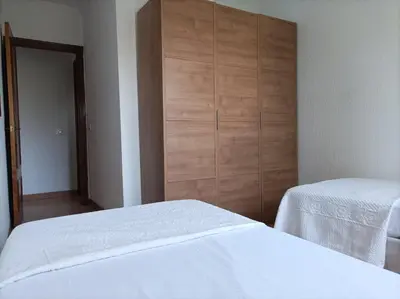 a bedroom with two beds and a wooden closet at 2 dormitorios y muy fácil aparcamiento in Jerez de la Frontera