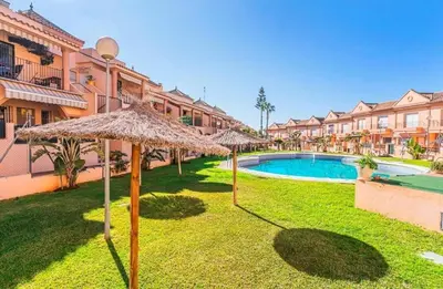 a resort with a swimming pool and umbrellas at Apartamento Al Andalus. La Barrosa. in Chiclana de la Frontera