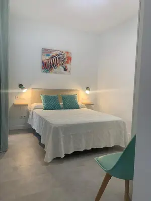 a bedroom with a bed with a painting on the wall at Apartamento Al Andalus. La Barrosa. in Chiclana de la Frontera