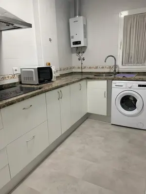 a white kitchen with a microwave and a washing machine at Apartamento Al Andalus. La Barrosa. in Chiclana de la Frontera