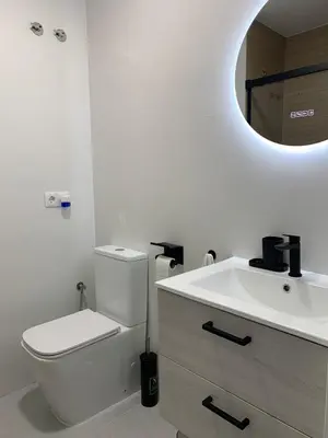 a white bathroom with a toilet and a sink at Apartamento Al Andalus. La Barrosa. in Chiclana de la Frontera
