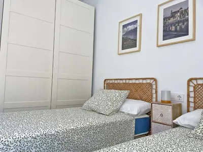 a bedroom with two beds and a cabinet at Apartamento El Carmen - Ole Solutions in Jerez de la Frontera