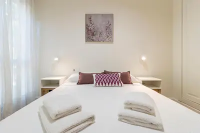 a white bedroom with a large white bed with towels on it at Allo Apartments Santo Domingo Parking 2 Habitaciones in Jerez de la Frontera