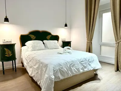 a bedroom with a large bed with white sheets at Apartamento Nebro Luna, En el Corazón de Cádiz in Cádiz