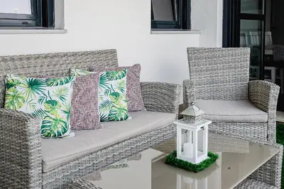 a rattan couch and two chairs with pillows and a table at Nautilus 3 - Elegante Apartamento para 6 con Piscina, Wifi y AC en Rota in Rota