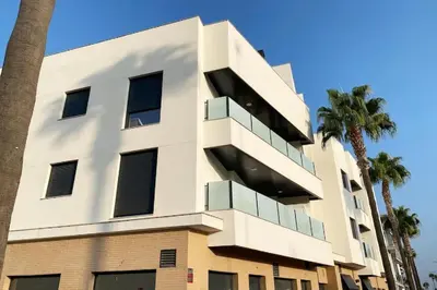 a white building with palm trees in front of it at Nautilus 3 - Elegante Apartamento para 6 con Piscina, Wifi y AC en Rota in Rota