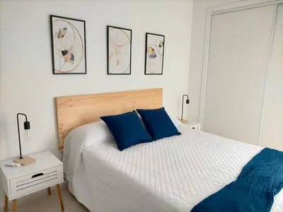 a bedroom with a white bed with blue pillows at Apartamento Lola Home in Sanlúcar de Barrameda