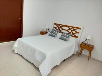 a bedroom with a large white bed with blue pillows at Apartamento Lola Home in Sanlúcar de Barrameda
