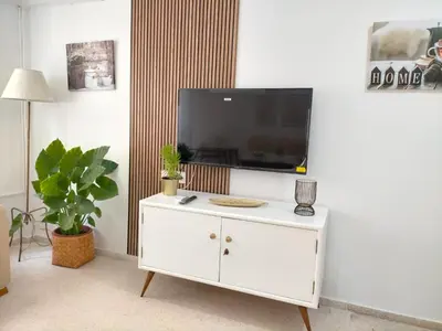 a living room with a white cabinet with a tv on it at Apartamento Lola Home in Sanlúcar de Barrameda
