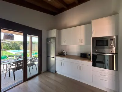 a kitchen with white cabinets and a table with a patio at Villas Magnolia y Brezo in Chiclana de la Frontera