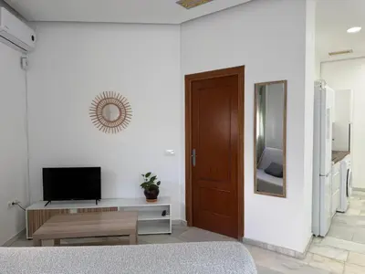 a white room with a television and a door at Salmedina in Sanlúcar de Barrameda