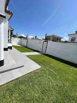 a white fence next to a yard with green grass at APOLO in Chiclana de la Frontera