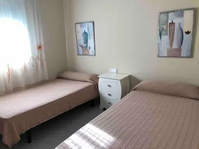 a bedroom with two beds and a dresser and a window at APOLO in Chiclana de la Frontera