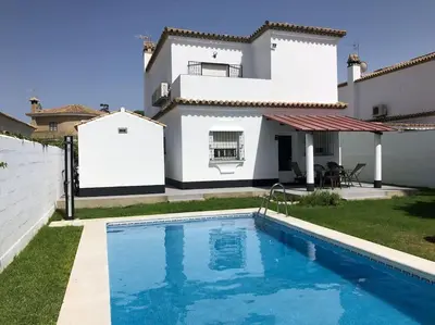 a villa with a swimming pool in front of a house at APOLO in Chiclana de la Frontera
