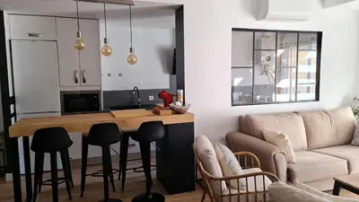a kitchen and living room with a table and a couch at Aires de Doñana. Piscina y Playa. Parking gratis. in Sanlúcar de Barrameda