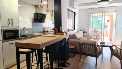 a kitchen and living room with a large wooden counter top at Aires de Doñana. Piscina y Playa. Parking gratis. in Sanlúcar de Barrameda