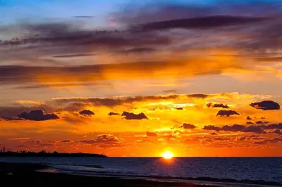 a sunset on the beach with the sun setting at Aires de Doñana. Piscina y Playa. Parking gratis. in Sanlúcar de Barrameda