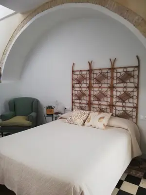 a bedroom with a white bed and a chair at Apartamento Arco´s House in Sanlúcar de Barrameda