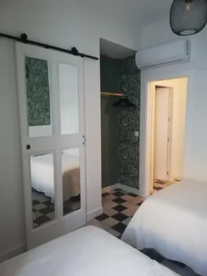 a room with two beds and a door with a mirror at Apartamento Arco´s House in Sanlúcar de Barrameda
