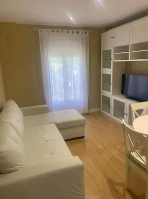 a living room with a white couch and a television at Ribeira en Playa Victoria Grupo AC Gestion in Cádiz