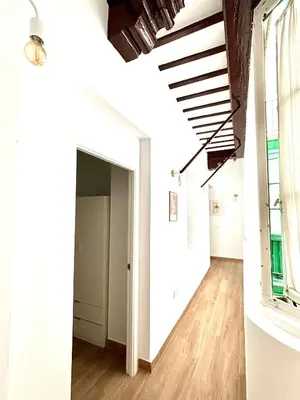 a hallway with white walls and wooden floors and a window at Tía Norica - Centro Cádiz in Cádiz