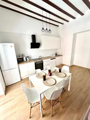 a white kitchen with a white table and chairs at Tía Norica - Centro Cádiz in Cádiz
