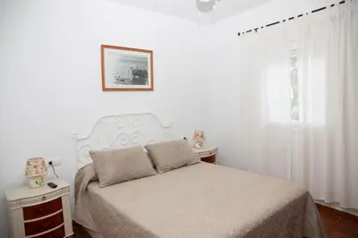 a white bedroom with a bed and a window at Poniente in Roche