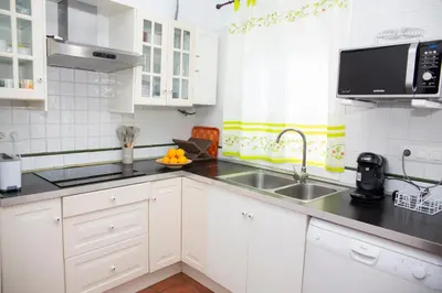 a kitchen with white cabinets and a sink at Poniente in Roche