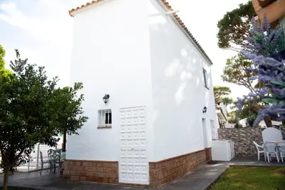 a white house with chairs and a fence at Poniente in Roche