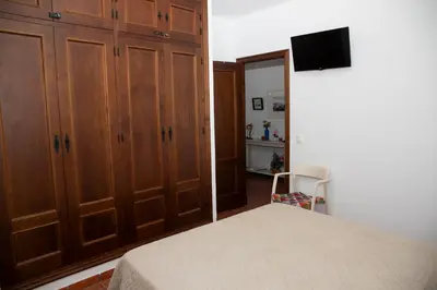 a bedroom with a bed and wooden cabinets and a television at Poniente in Roche
