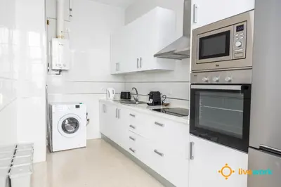a white kitchen with a microwave and a washer and dryer at Apartamento Bike by LiveWork in Cádiz
