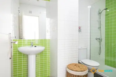 a green and white bathroom with a sink and a toilet at Apartamento Bike by LiveWork in Cádiz