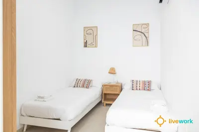 two beds in a room with white walls at Apartamento Bike by LiveWork in Cádiz